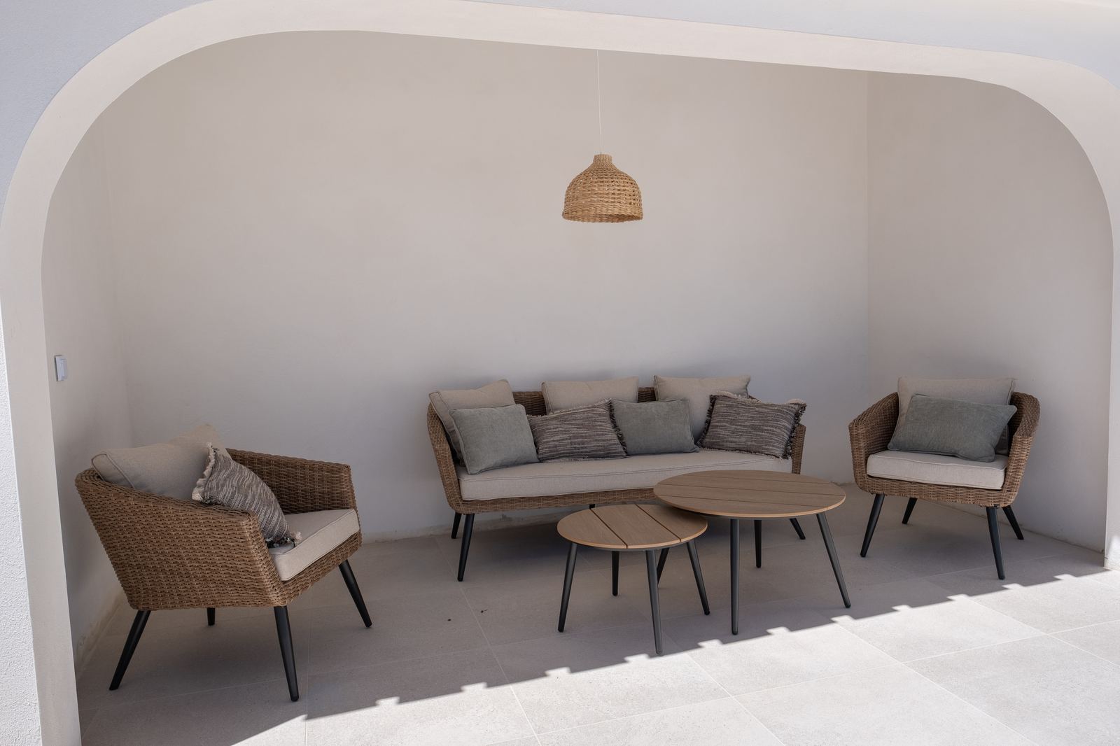 Overdekte patio met loungeset onder een rieten hanglamp