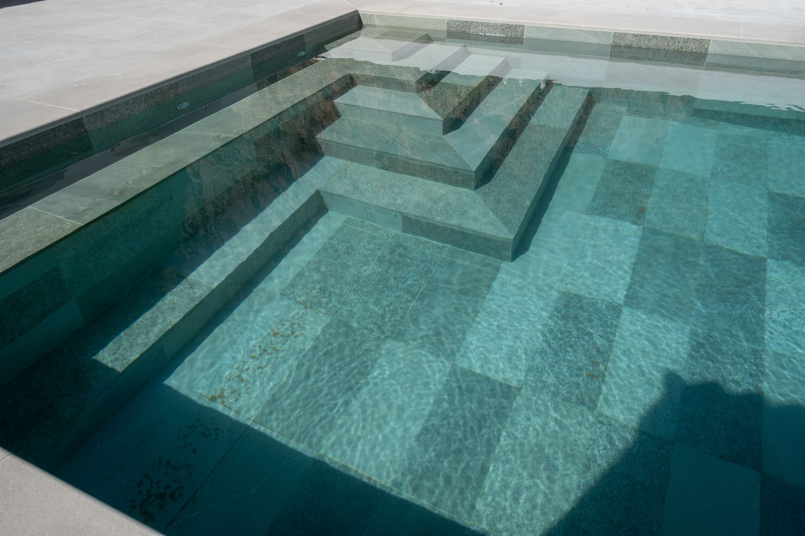 De brede trap van het vernieuwde zoutwaterzwembad in helder turquoise water
